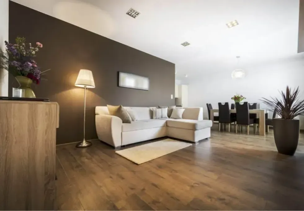 Premium wide-plank hardwood flooring supply installed in a modern Calgary open-concept living room, featuring a rich walnut finish and durable matte coating