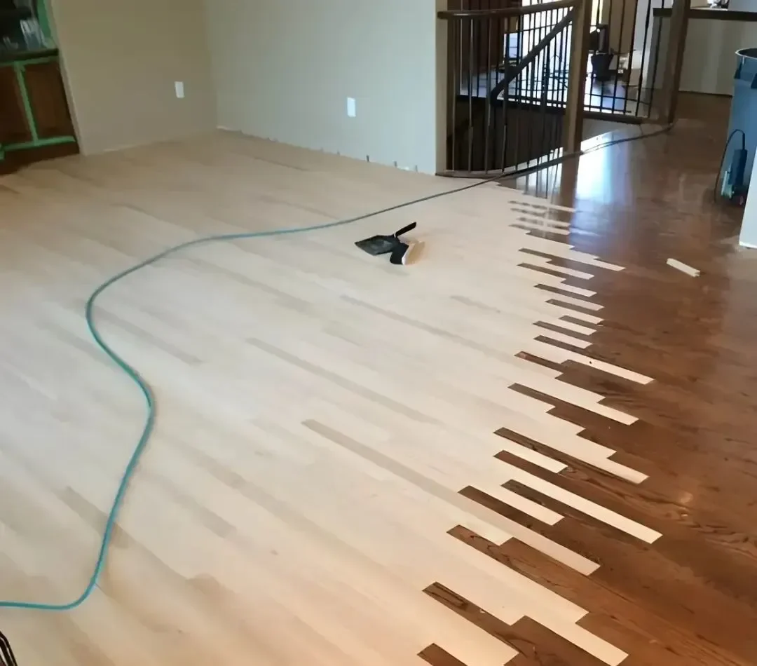 Professional hardwood floor repair featuring new light wood planks being woven or 'laced' into an existing dark-stained floor to create a seamless transition before sanding